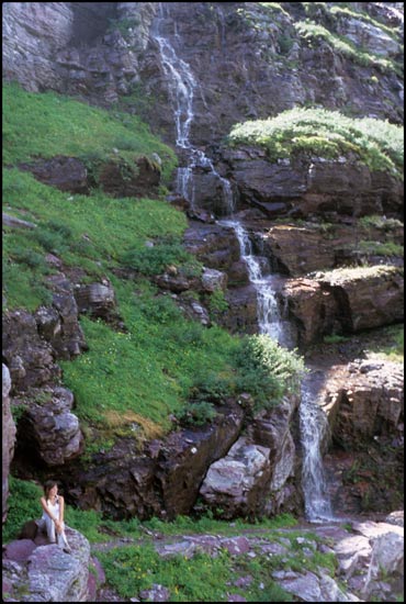 - Hiker Relaxing Below a Waterfall, Glacier NP -